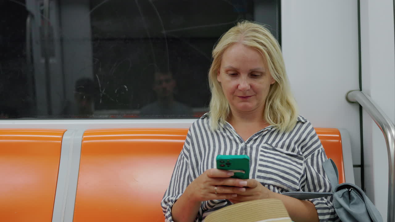 Woman using smartphone while sitting in subway train, urban commute and modern lifestyle concept