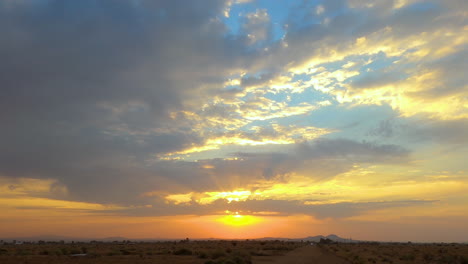 Driving-along-on-a-dirt-road-in-the-Mojave-Desert-heading-straight-towards-the-sunset---concept-idiom:-riding-off-into-the-sunset