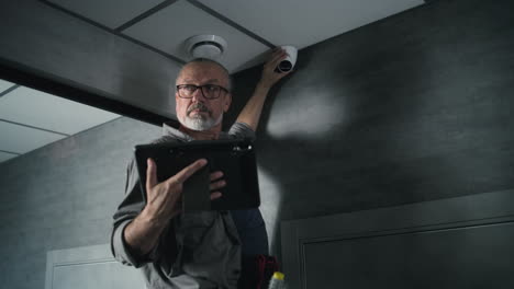 technician installing security camera with tablet