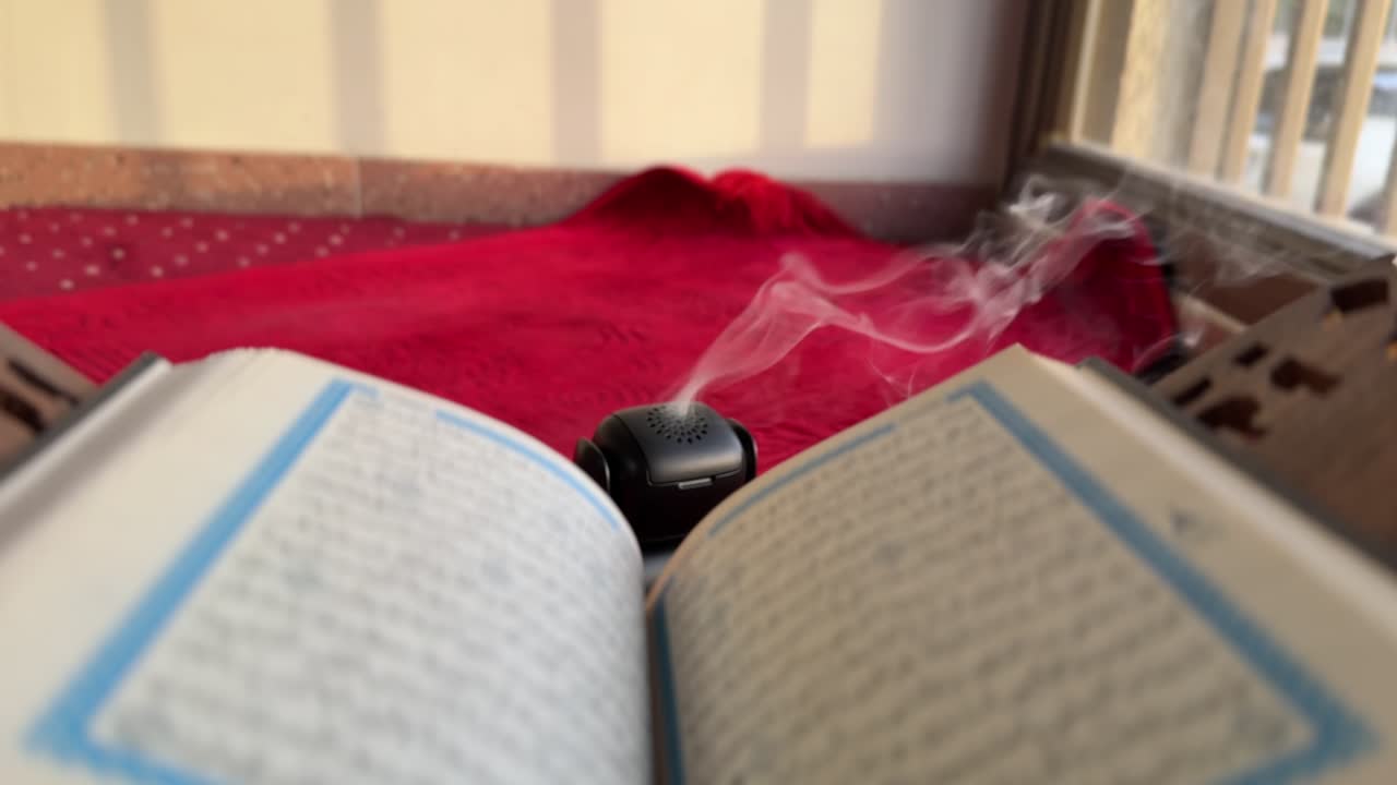 4K footage of a Holy Quran with rising incense smoke on a red prayer mat in a calm setting. Ideal for Ramadan, Islamic content, spirituality, and peaceful ambiance themes.