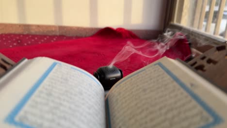 4k footage of a holy quran with rising incense smoke on a red prayer mat in a calm setting. ideal for ramadan, islamic content, spirituality, and peaceful ambiance themes.