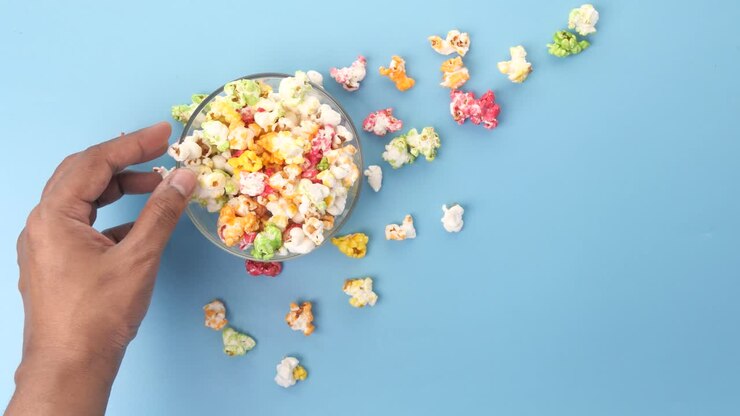 Mano che prende popcorn colorati da una ciotola
