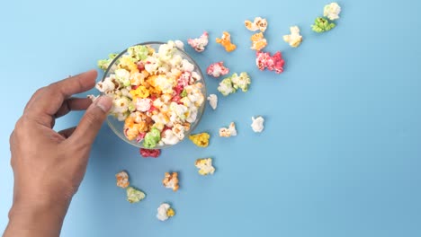 hand reaching into a bowl of colorful popcorn