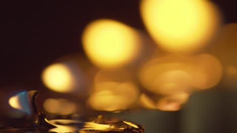 a candle struggles to burn in the gentle wind of the night - static macro shot with golden bokeh in the background