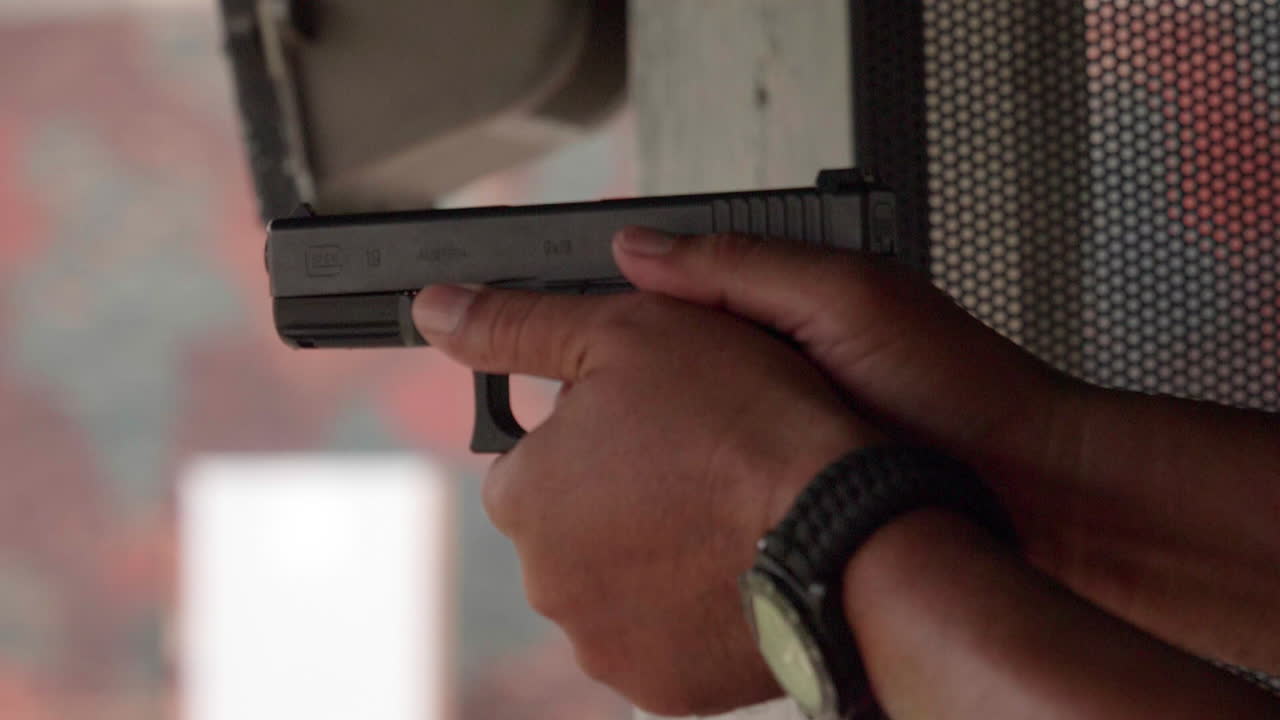 Slow motion scenes of The gun firing at a shooting range on the man hand withhold the gun tight and pull the trigger