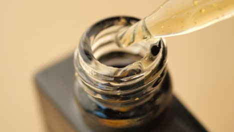 pouring gold serum into dark glass bottle