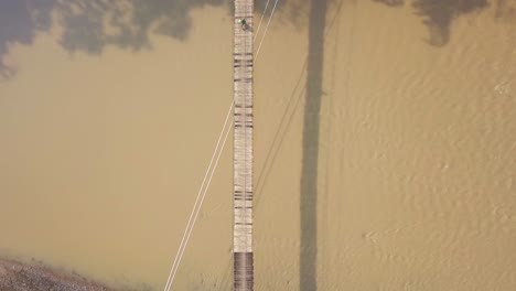 Drone-shot-of-people-walking-on-the-wooden-suspension-bridge