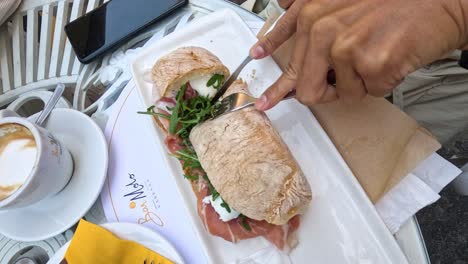 cutting a sandwich at a café table