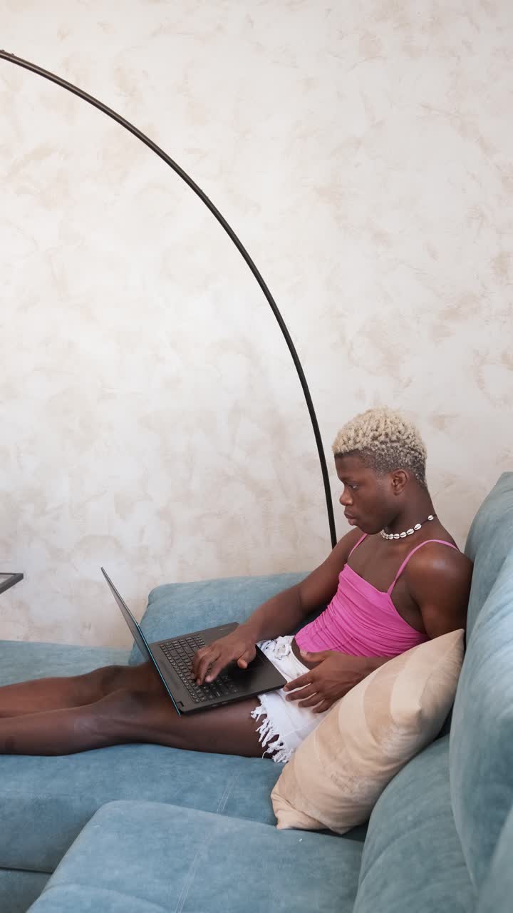 Person working on a laptop while relaxing on a couch