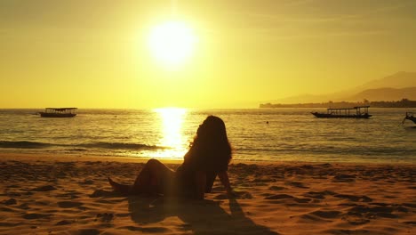 Silueta-De-Una-Chica-Meditando-En-Una-Playa-Exótica-Al-Atardecer-Mágico-Con-Un-Cielo-Amarillo-Reflejado-En-Una-Laguna-Tranquila-Con-Barcos-Flotando-En-Tailandia