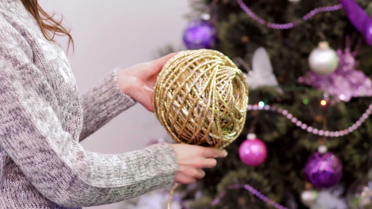 chica enrolla una bola de hilo dorado