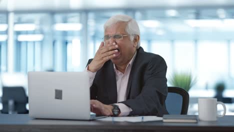 sleepy and lazy senior indian manager working on laptop