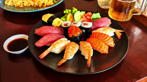 a close-up of a fresh and delicious platter of assorted japanese sushi and sashimi, including salmon, tuna, and shrimp nigiri, served with soy sauce for dinner