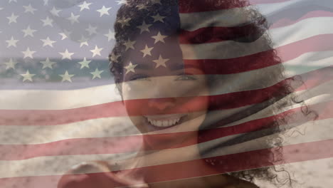 animation of flag of america over portrait of smiling african american young woman at beach