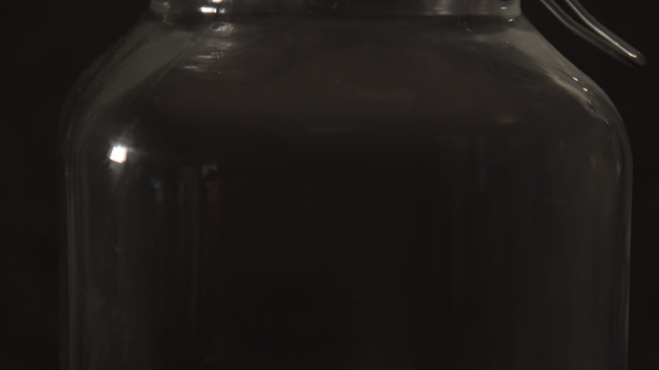 крупный план стеклянной банки для консервирования с металлическим кронштейном на черном фоне