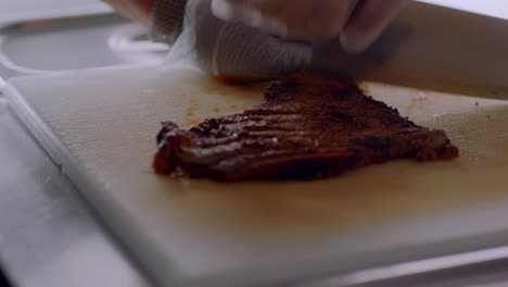 person precisely cutting steak on wooden board