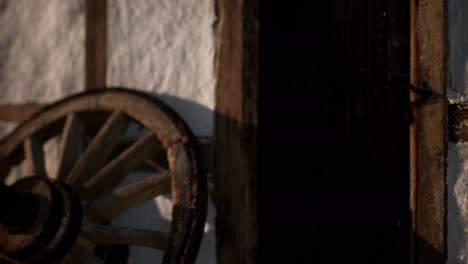 old wood wheel and black door at white house