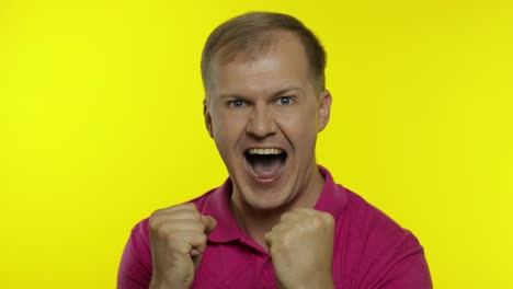 portrait of young caucasian man posing in pink t-shirt. satisfied handsome guy celebrates, wins