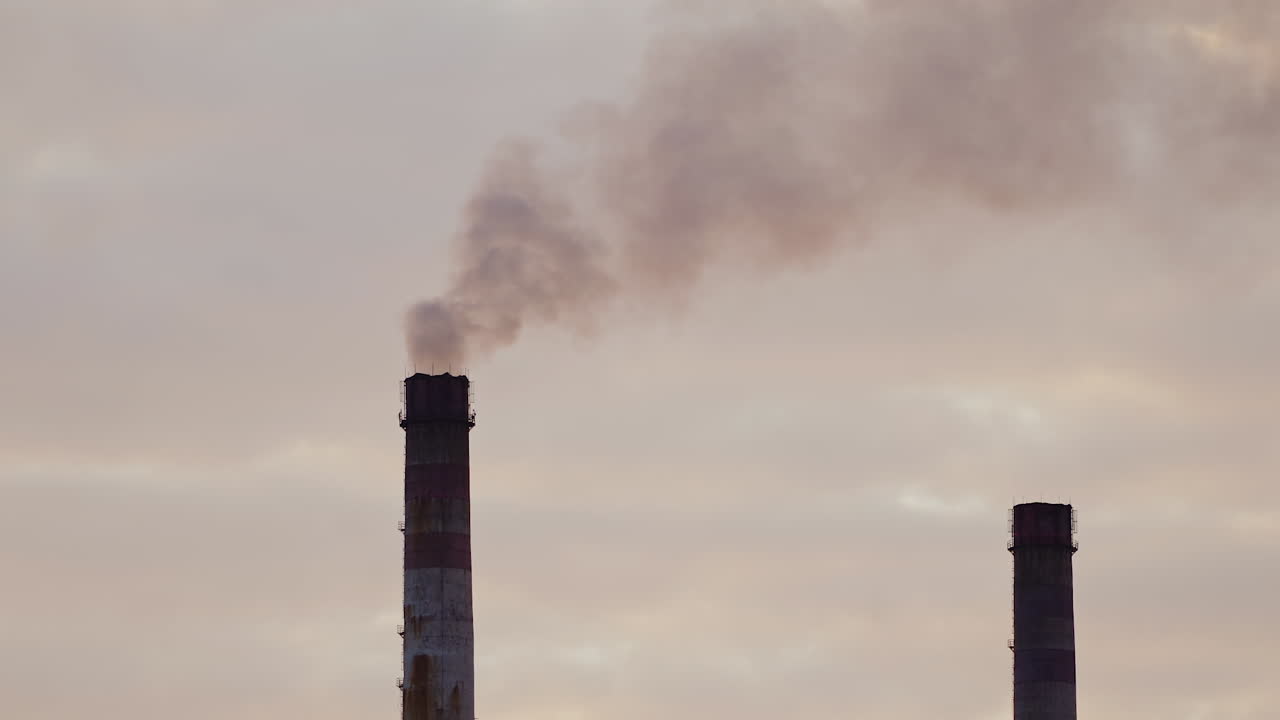 Industrial pipes with massive smoke. Harmful emissions fill the air on the evening sky background. Dense fumes pollute the atmosphere. Ecological disaster. Close-up