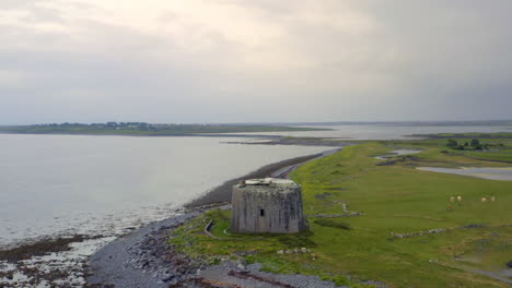 establishing aerial shot of aughinish martello tower and its narrow causeway linking to the mainland in galway bay