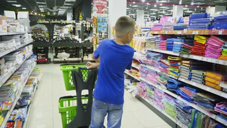 vinnitsa, ukraine - august, 2018: boy chooses office supplies. many colorful tools and supplies on the shelf of a stationery shop