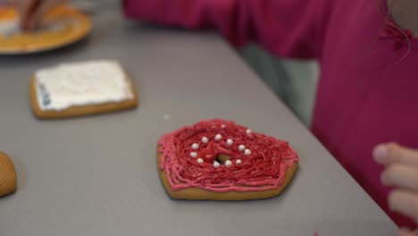 close up view of kids hands decorating homemade cookies for holidays. a child decorates cookies pressing out fondant or paste from a tube