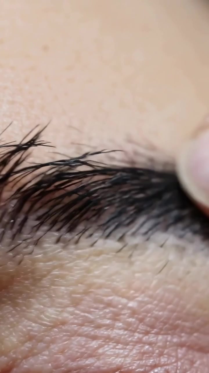 Vertical video: Pressing thumbnail and index finger checking eyebrow hair direction in close-up