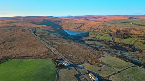 Imágenes-Aéreas-De-Drones-Del-Tráfico-En-Una-Carretera-Rural-En-El-Páramo-De-Saddleworth-Con-Lago-De-Tierra-Dorada,-Embalse-Y-Amplias-Vistas-Abiertas-De-Los-Peninos