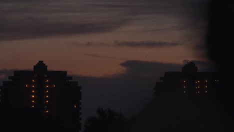 Resort hotel buildings at sunset with beautiful color clouds as elevators move through building time lapse