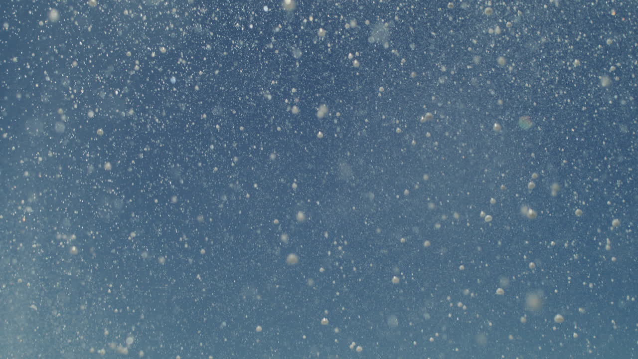 Ocean spray pattern creates shimmering textures in light as foam floats upward in motion