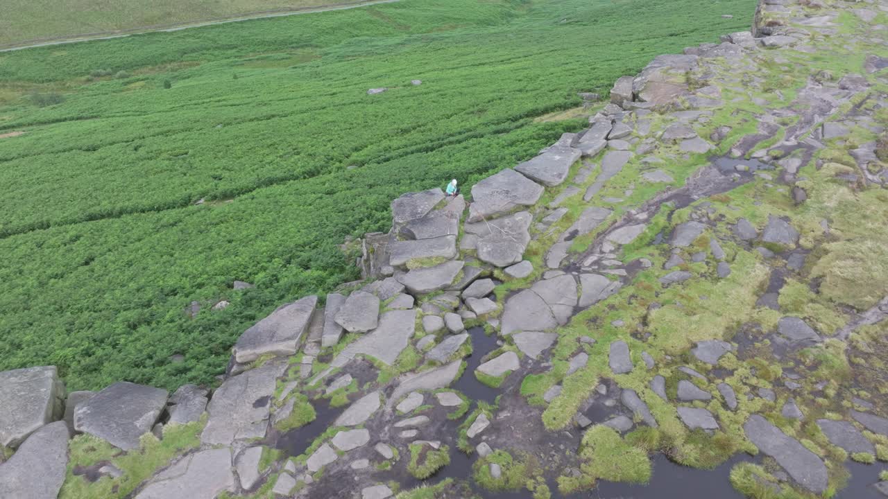 등반자는 스테이지 가장자리에 있는 비석 절벽에 앉아 있으며, 덤불 지대 위에서 공중으로 밀어 넣습니다.