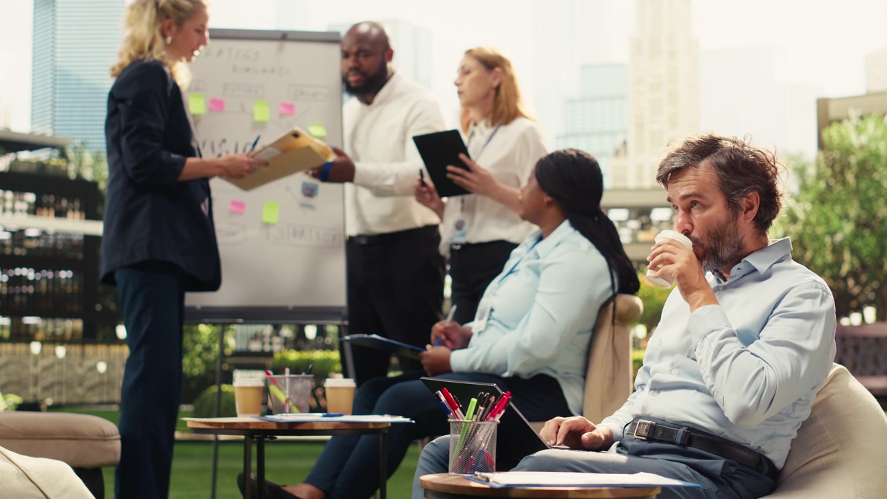 Man Working on Laptop While Colleagues Collaborate in Background
