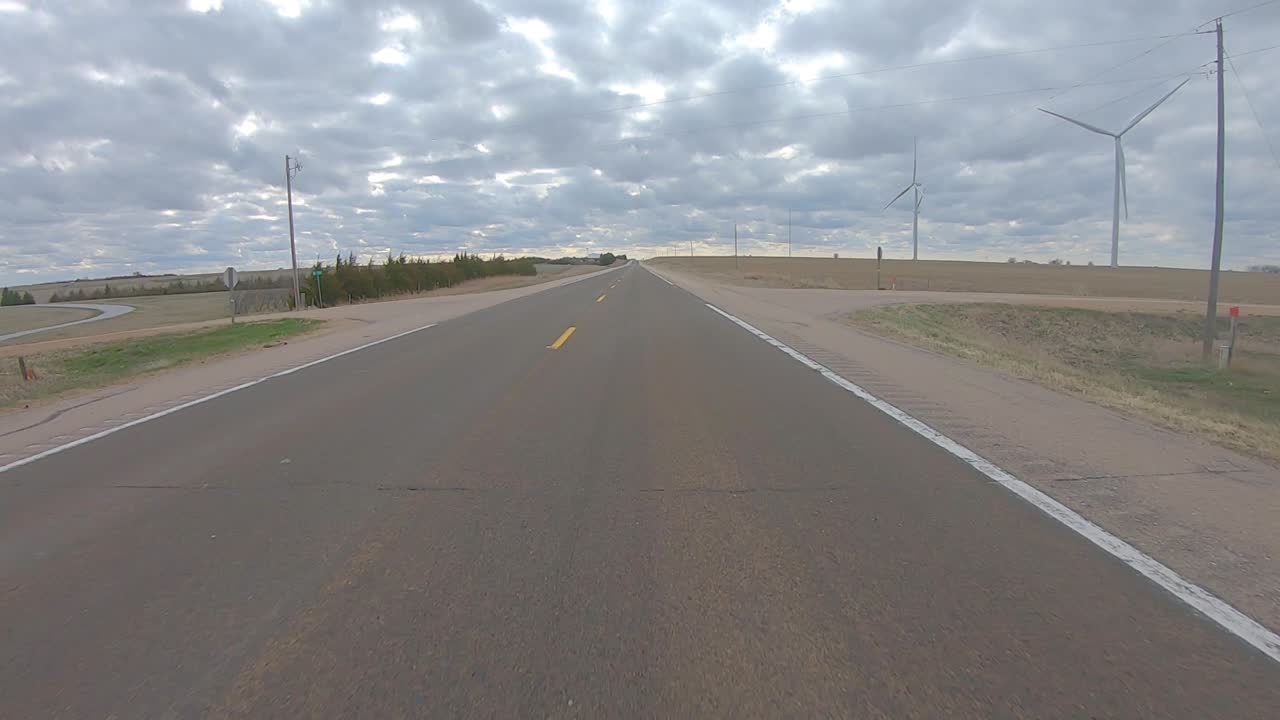 이른 봄에 흐린 날 남부 네브래스카 시골의 풍력 터빈을 지나 조용한 고속도로에서 운전