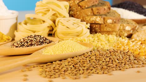 a variety of grains and pasta arranged on a wooden surface under bright lighting, creating a vibrant and inviting scene