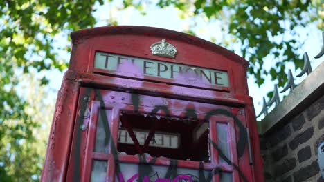 clip of the vandalized telephone booth with broken glass and graffiti paint