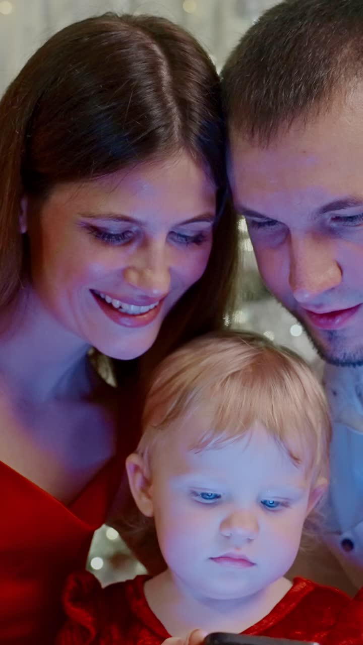 Un momento di unione familiare: genitori che interagiscono con il proprio figlio mentre usano uno smartphone in un ambiente accogliente, mettendo in risalto la gioia e la curiosità dell'infanzia durante un'occasione speciale