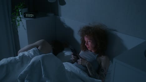 pareja en la cama usando teléfonos inteligentes por la noche