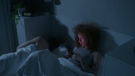 couple in bed using smartphones at night