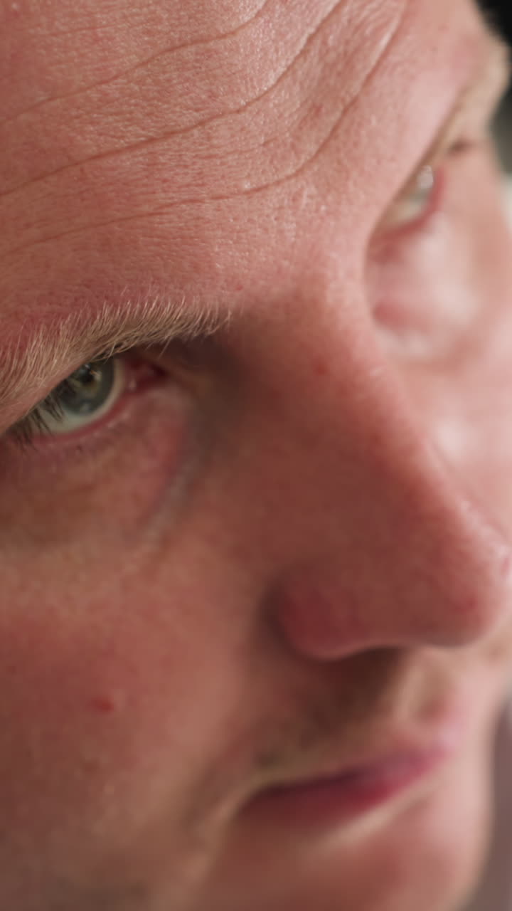 una vista en primer plano de un técnico con bata blanca de laboratorio y guantes negros apoyando su cabeza en su brazo izquierdo, mostrando un momento de fatiga