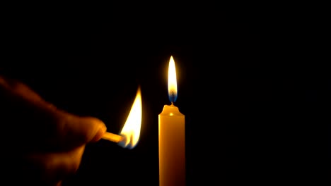 a single white candle burning. looping for use as a background or illustration of remembrance or celebration. the wind tries to put out the flame, but it recovers each time. the eternal flame.