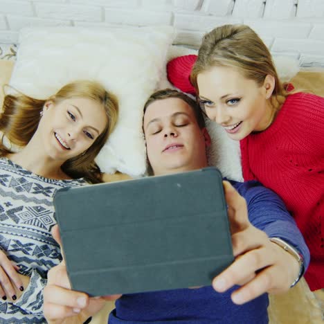 tres amigos se acuestan en la cama para charlar en la vista superior de skype