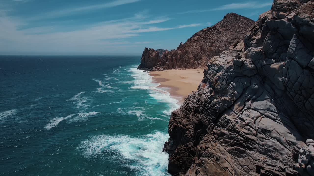 Aerial footage of ocean waves rolling in along the beach in Cabo San Lucas, Mexico