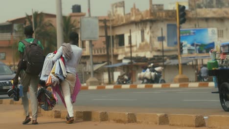 African-Clothes-and-tea-street-vendors-walking-by---Togo,-Africa