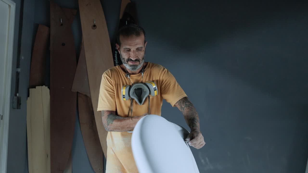 hombre enfocado usando papel de lija en la tabla de surf