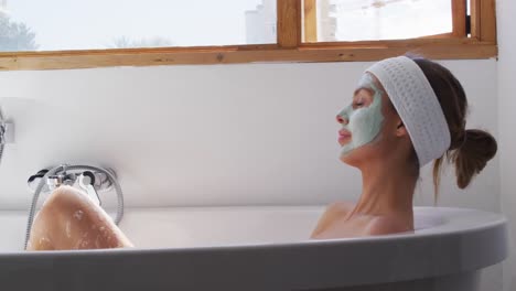 woman wearing face pack relaxing in bathtub