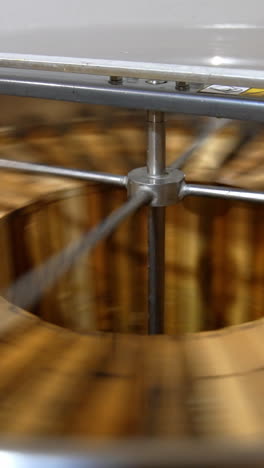 rotating mechanism working inside the metal barrel. electric centrifuge machine extracting honey from frames. close up. vertical video