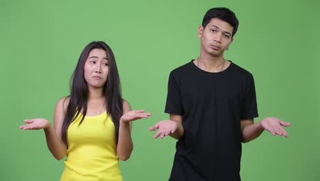 young asian couple shrugging together