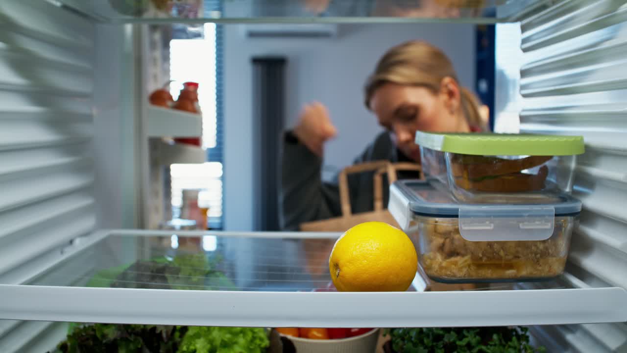 mujer buscando en el refrigerador para encontrar comida para el almuerzo o la cena