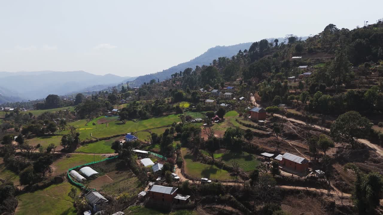 Scenic footage of a Nepalese village surrounded by green paddy fields and mountains. Highlights rural lifestyle, natural beauty, and peaceful countryside environment