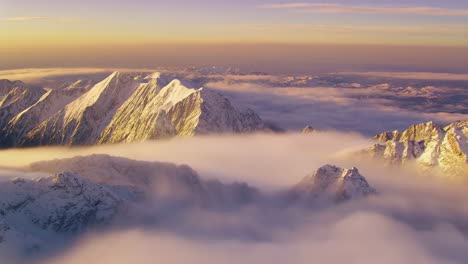 majestic snow-capped mountains emerging from clouds at sunset